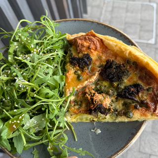Tarte aux brocolis, petits pois, emmental et chèvre, servie avec une salade de roquette.